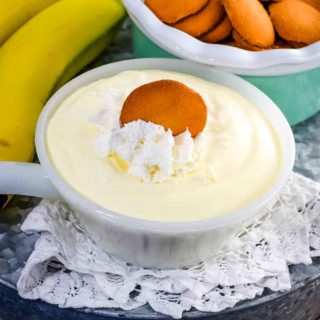 a small white bowl filled with this easy banana pudding recipe topped with whipped cream and a vanilla wafer