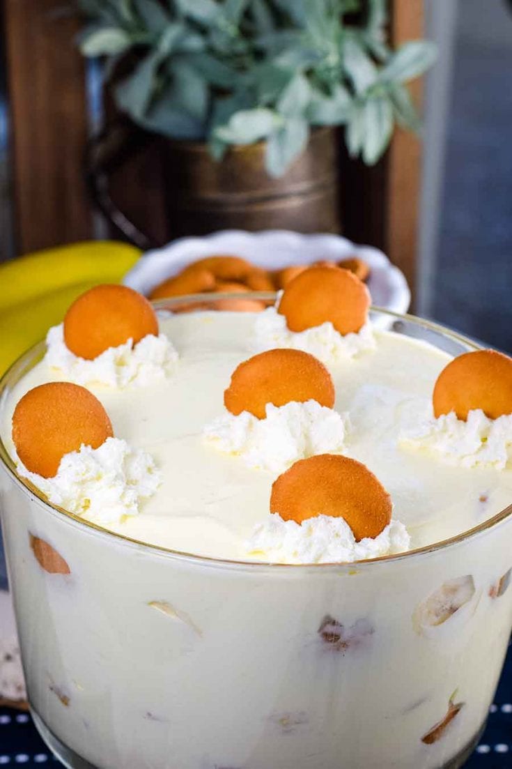 A large glass serving bowl filled with this easy banana pudding recipe topped with whipped cream and a vanilla wafers 