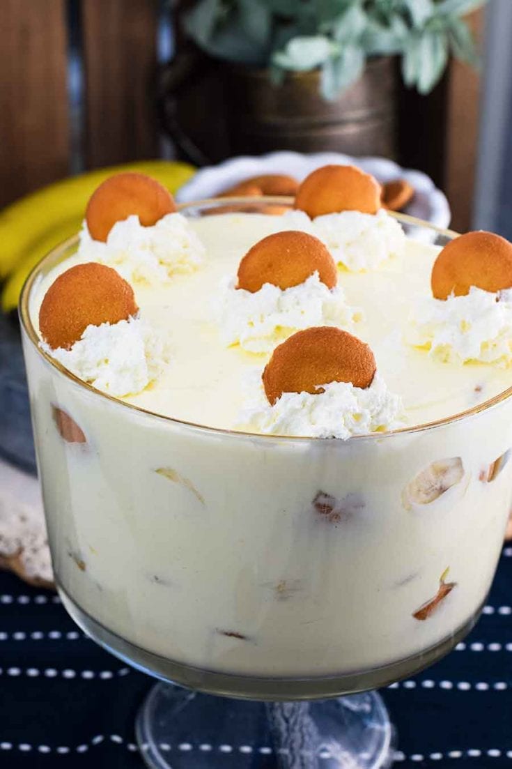 A large glass serving bowl filled with this easy banana pudding recipe topped with whipped cream and a vanilla wafers 