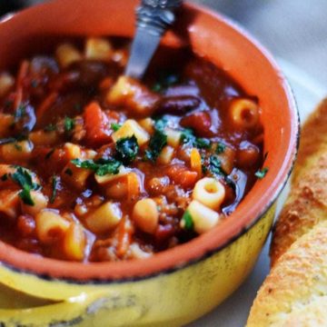 an overhead view of this pasta fagioli soup recipe inside of a stoneware bowl with handles and crispy bread