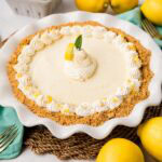 A whole no bake lemon Icebox pie in a white pie plate garnish with whipped cream, a lemon wedge, and mint leaves.