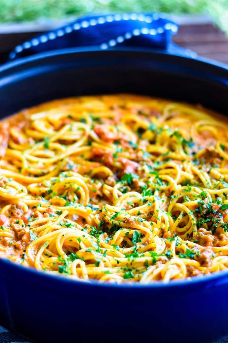 Sausage Spaghetti with a Spicy Creamy Tomato Sauce in a blue cast iron enameled skillet.