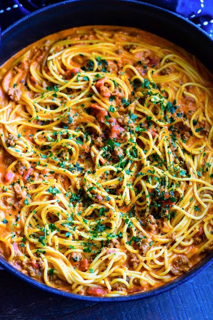 Sausage Spaghetti with a Spicy Creamy Tomato Sauce in a blue cast iron enameled skillet.