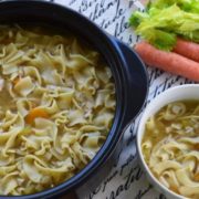 an overhead view of this stovetop chicken noodle soup recipe in a dutch oven and a white serving bowl