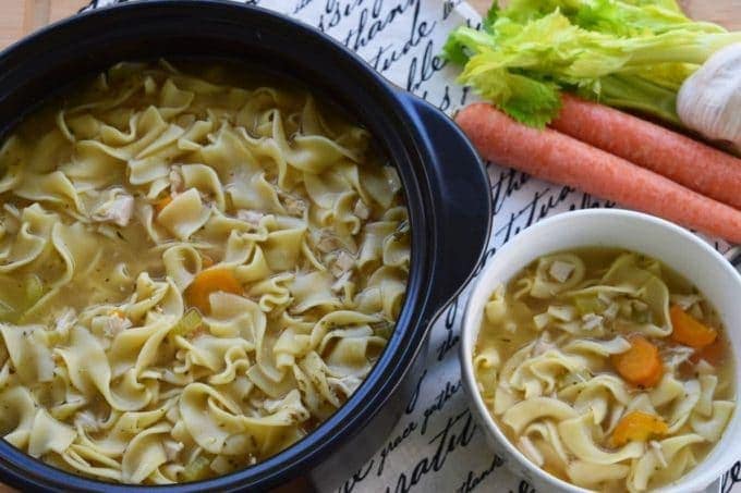 an overhead view of this stovetop chicken noodle soup recipe in a dutch oven and a white serving bowl