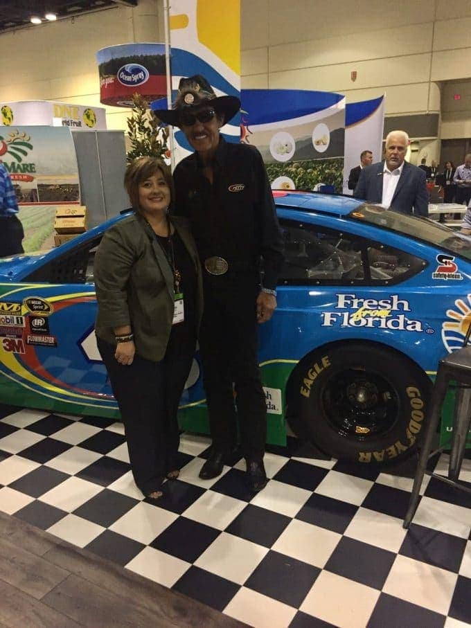 a woman and Richard Pettey standing in front of a blue race car
