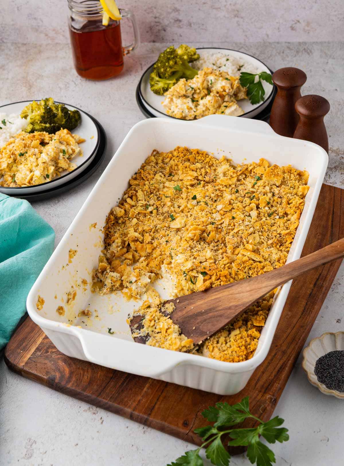 A 9 x 13 casserole dish filled with chicken poppyseed casserole with some of the casserole spoon out with a wooden spatula.