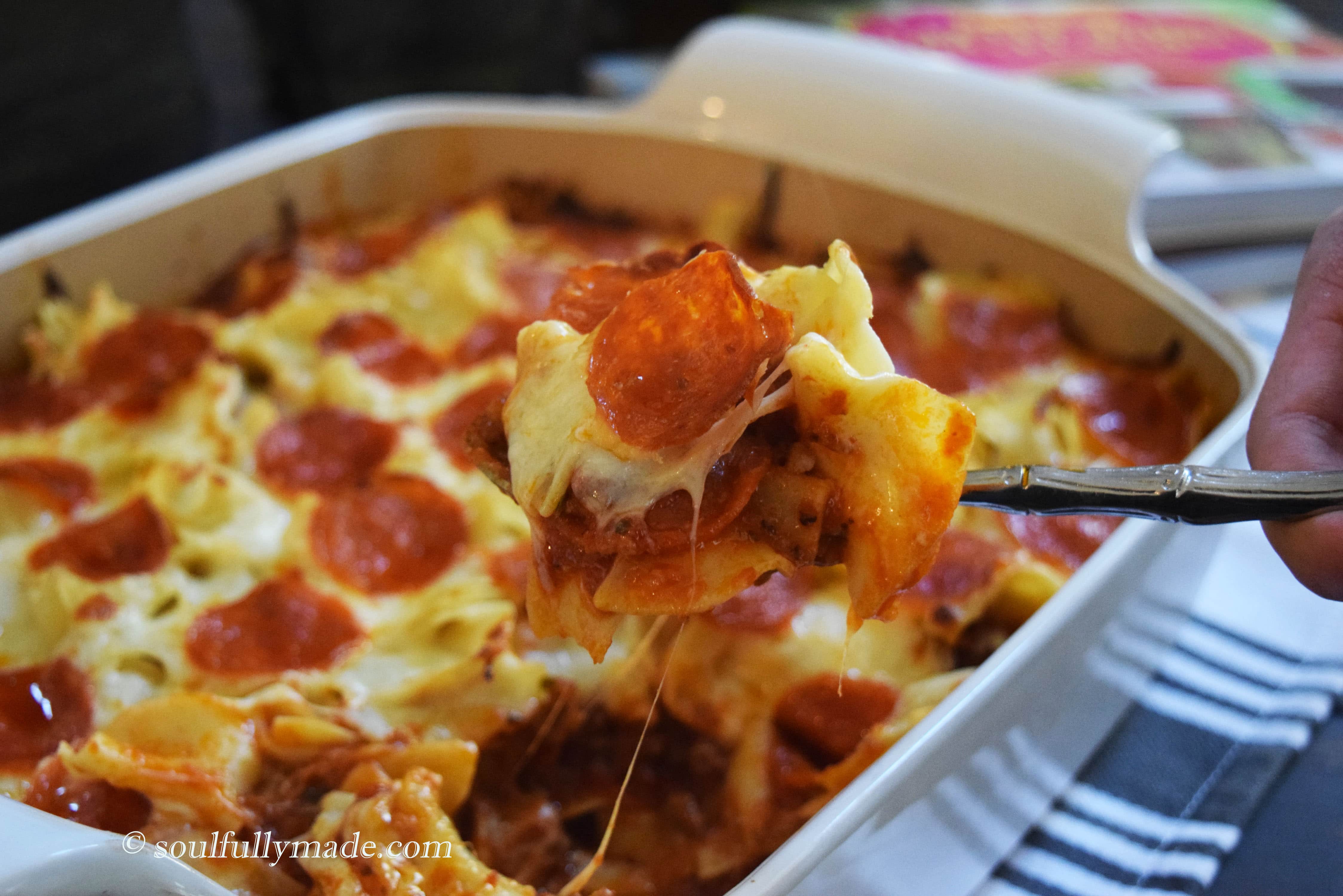 a spoon scooping up a serving of this pizza noodle bake