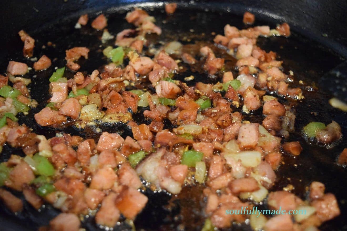 chopped andouille sausage and mirepoix sautéing in a black cast iron skillet