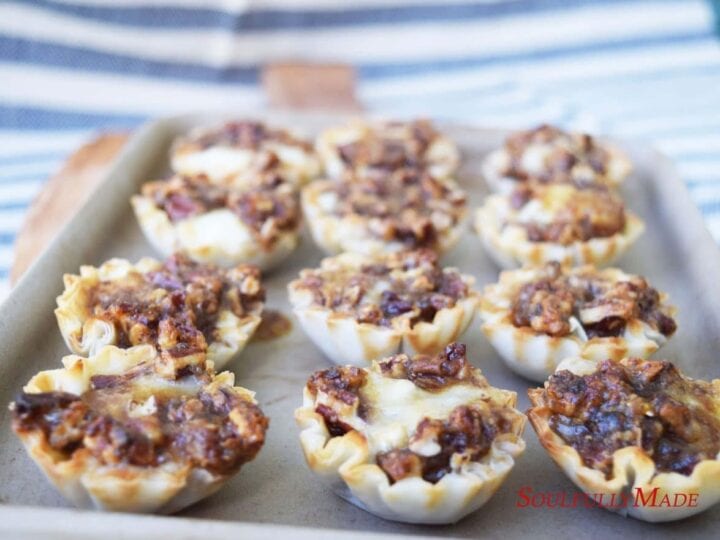 a closeup of these sweet dijon pecan baked brie fillo bites on a baking sheet