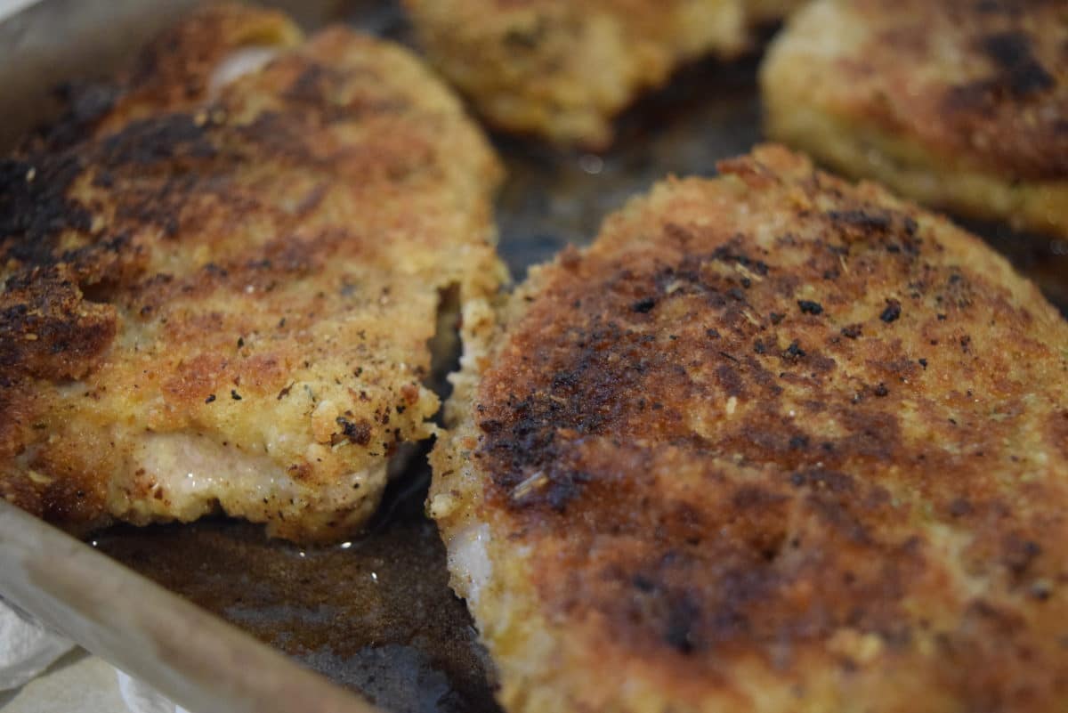 a closeup of these pan-fried fontina pork chops cooking in a skillet