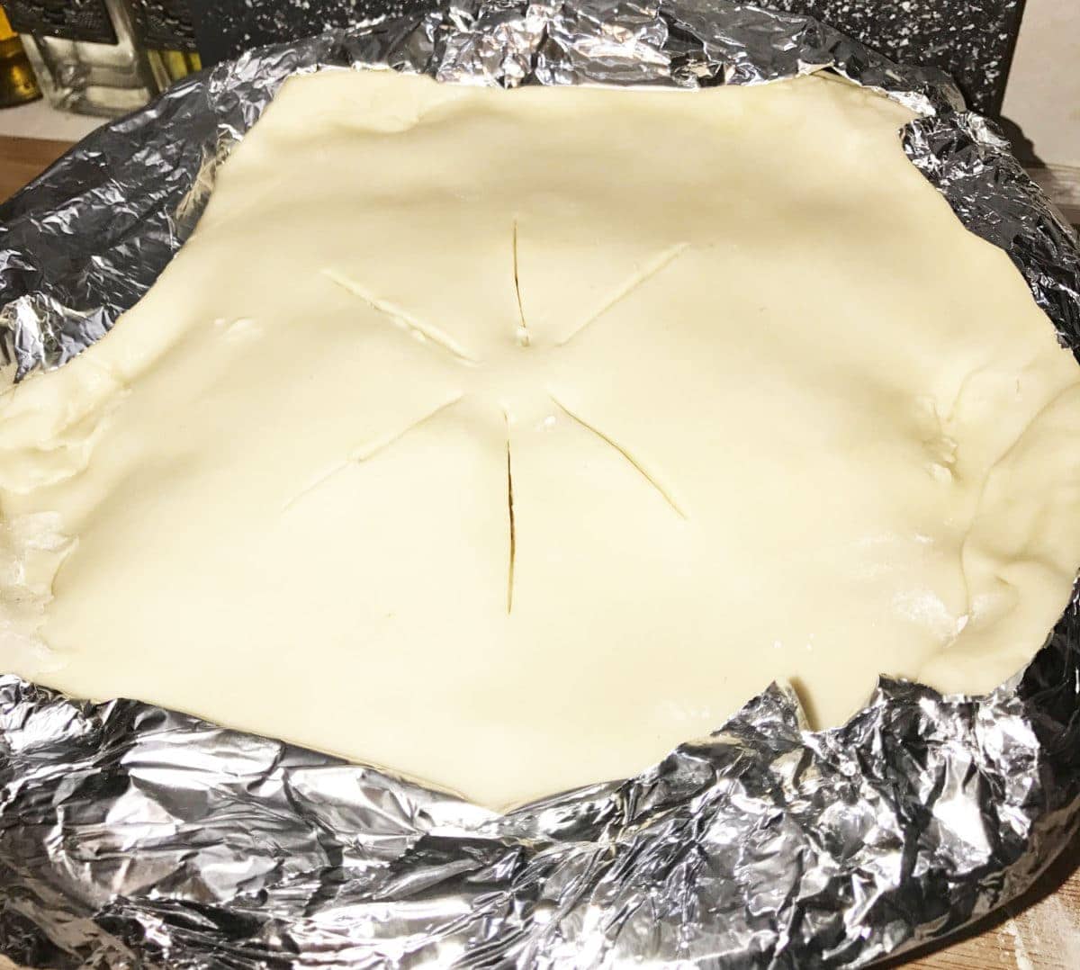 the pie crust laid over the uncooked chicken pot pie
