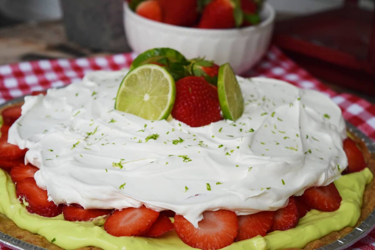 Strawberry Margarita Pizza topped with Whipped Cream and garnished with limes and strawberries