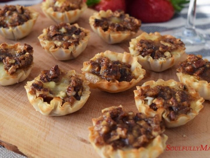 a closeup of these sweet dijon pecan baked brie bites on a wooden cutting board