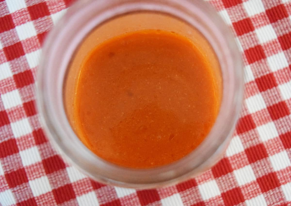 a glass bowl of homemade buffalo sauce