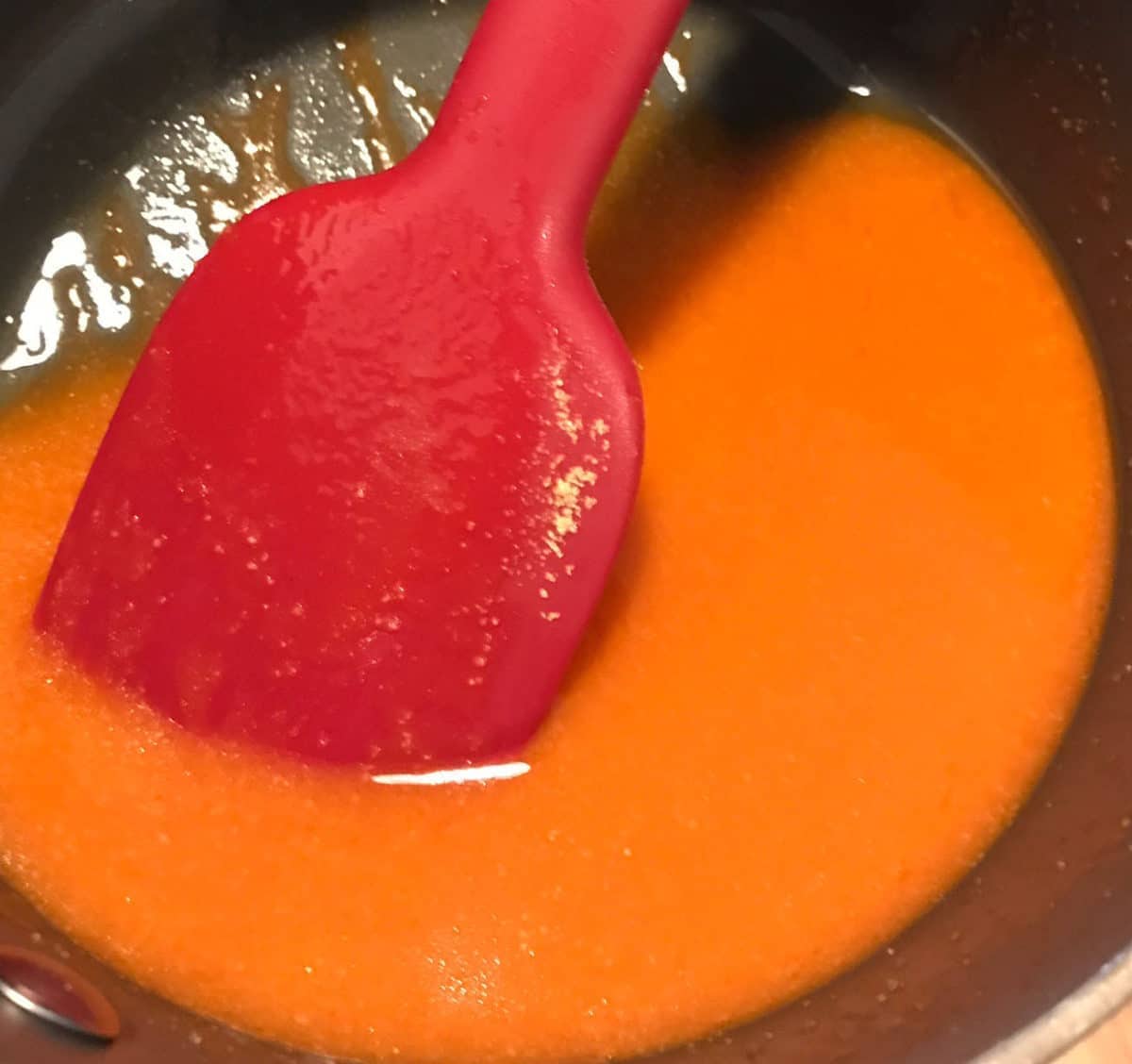 a red spatula inside of a bowl filled with this homemade buffalo sauce