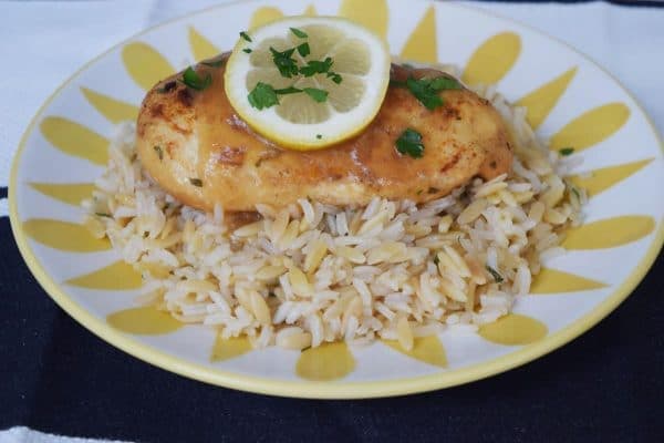 Lemon and Garlic Chicken on bed of rice pilaf garnished with lemon and parsley.