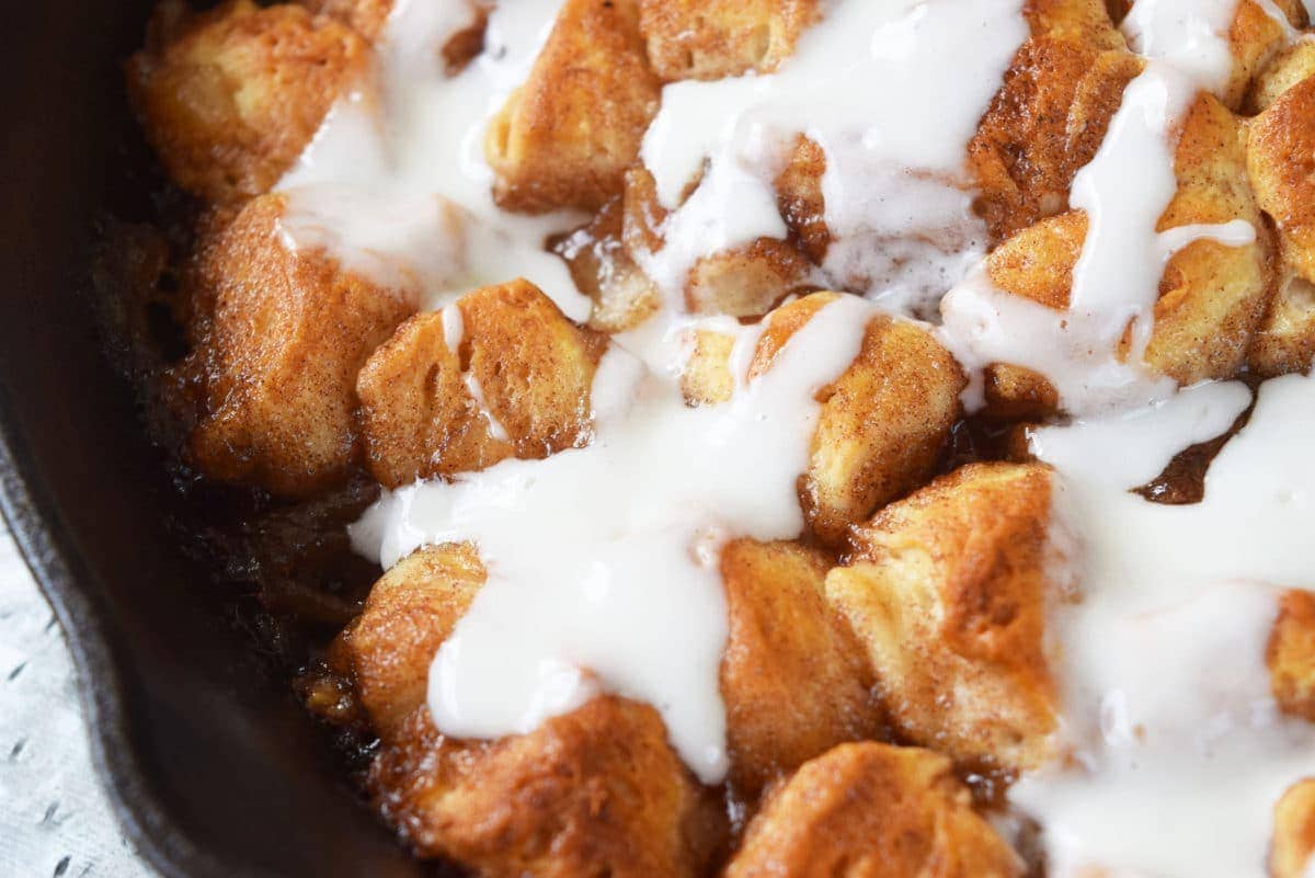 a closeup of the cooked skillet apple pie biscuit bites topped with a sweet glaze