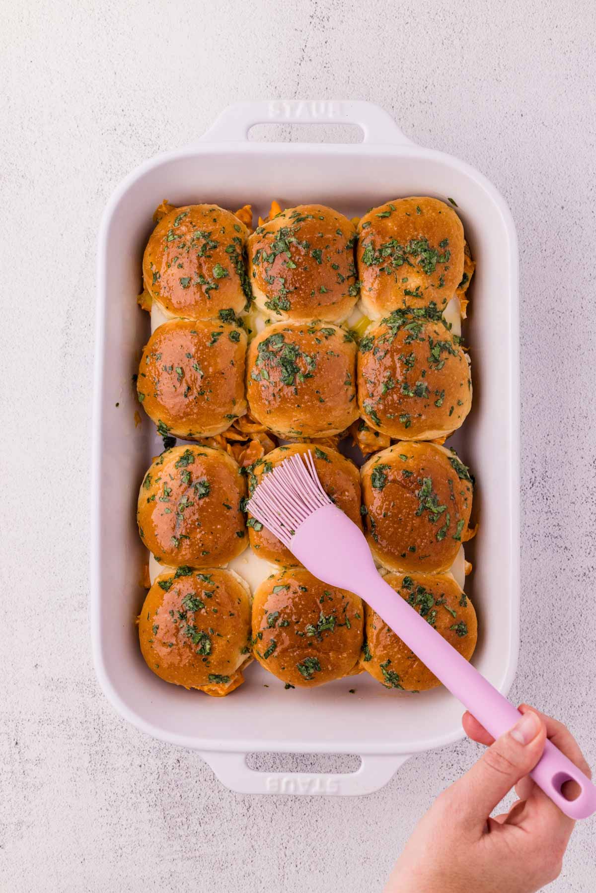 Spreading topping on the sliders with a silicone brush.