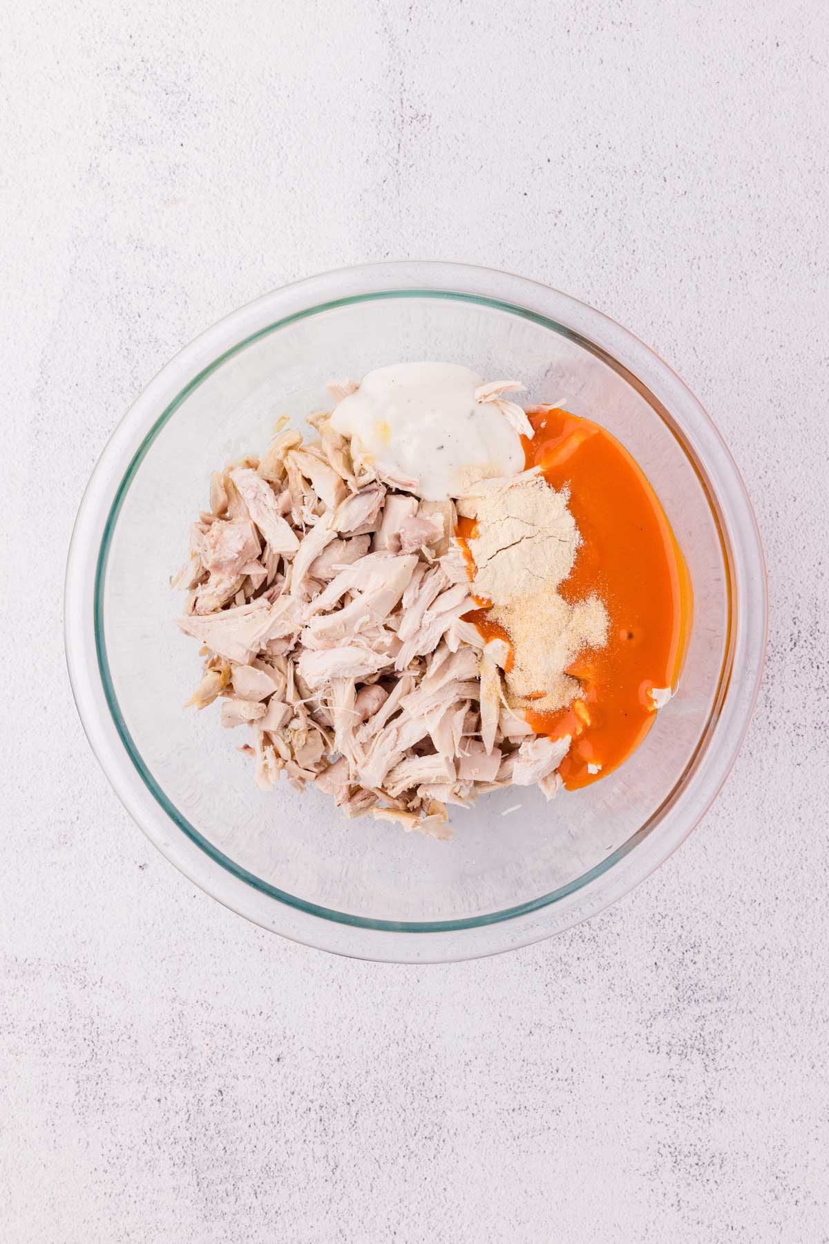 Shredded Chicken, buffalo sauce, ranch dressing, garlic powder, and onion powder in a bowl.