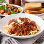 Spaghetti pasta with meat sauce in a white bowl.