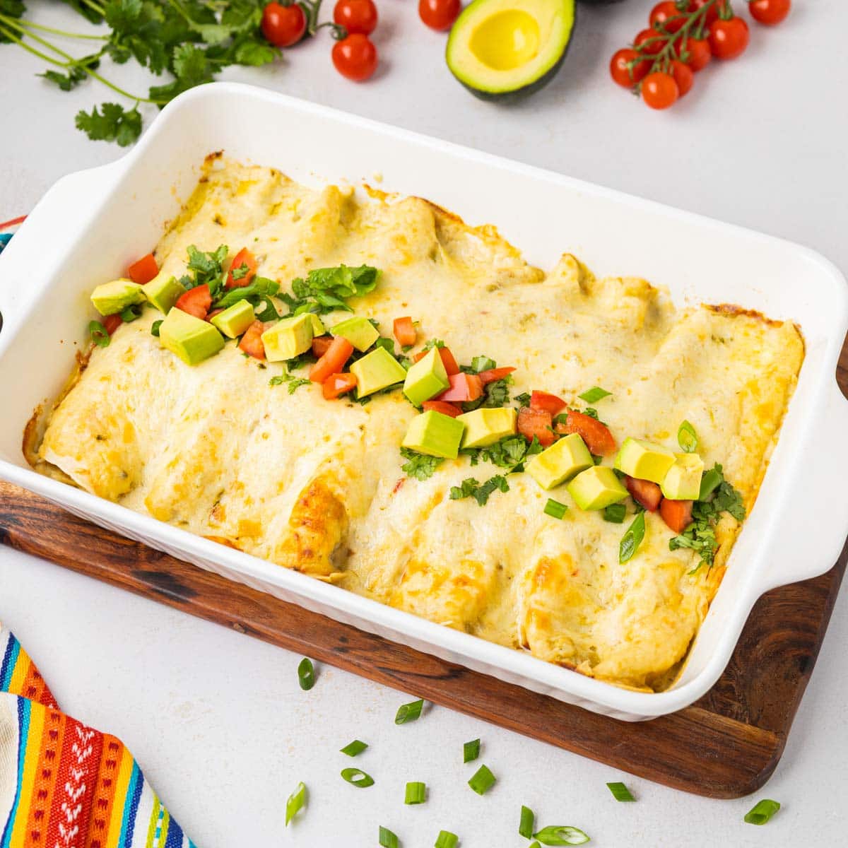 Green chile enchiladas in a white casserole dish.