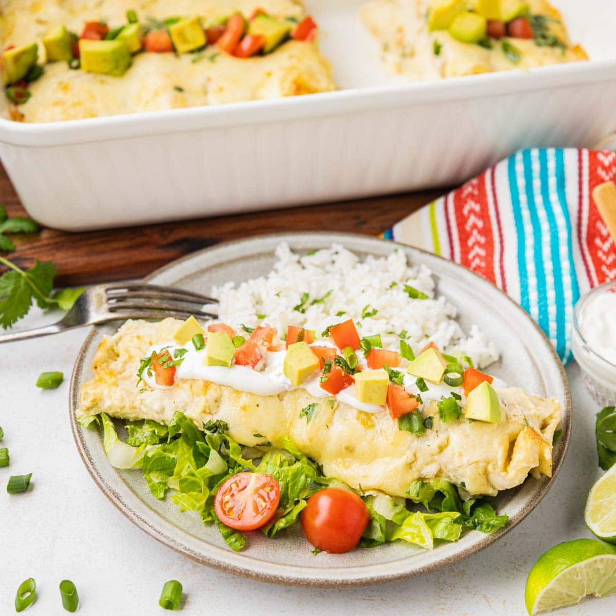 Green chile chicken enchilada on a plate with cilantro rice and salad.