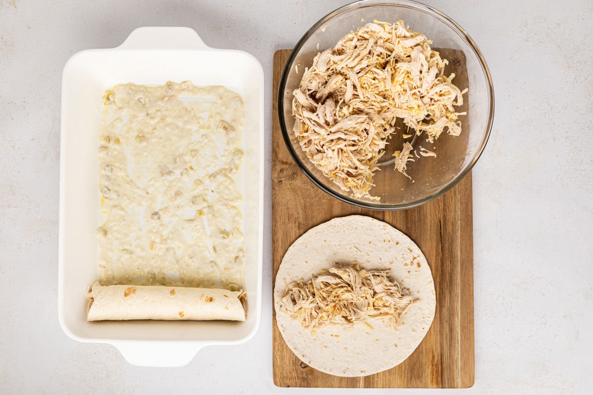 Rolled enchiladas added to the casserole dish with a light layer of sauce in the bottom.