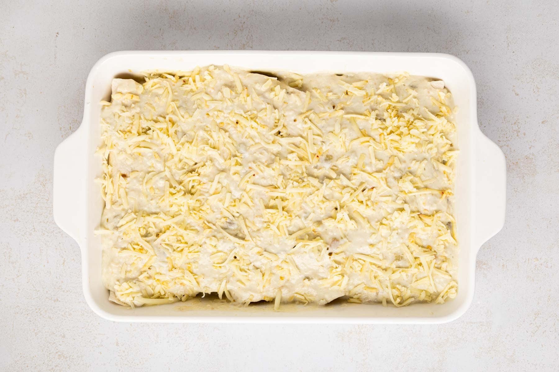 Cheese layered on top of enchiladas sauce.