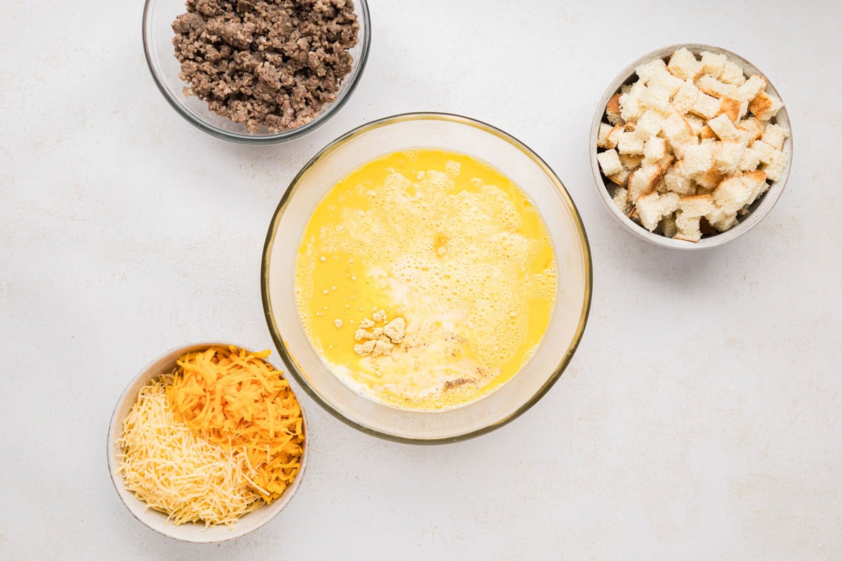 Whisked eggs in a bowl with milk and seasonings.