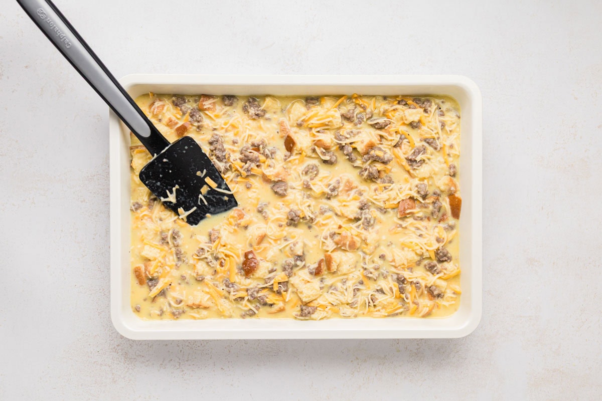 Overnight breakfast casserole poured into white baking dish.