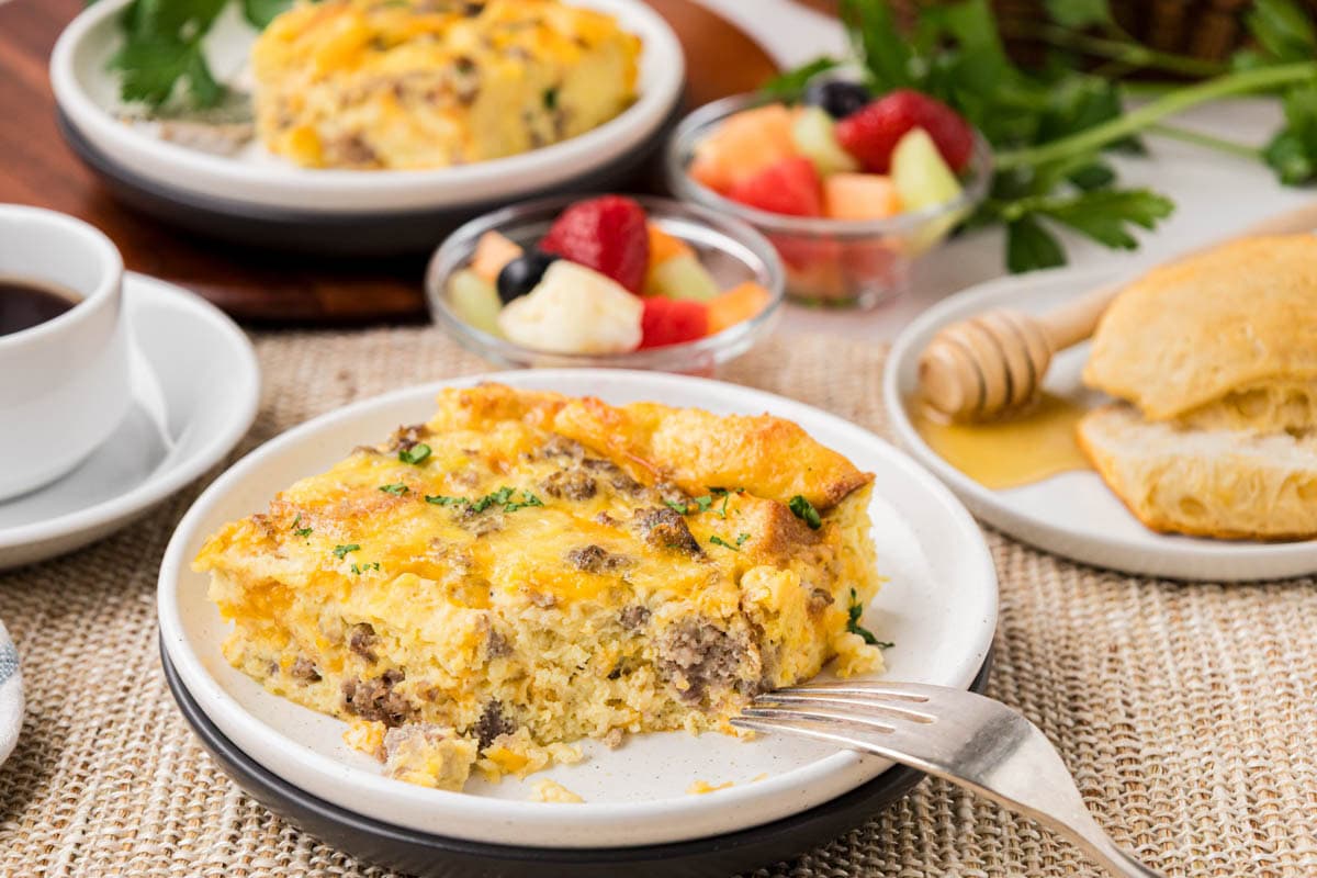 A slice of sausage breakfast casserole on a white plate with a bite removed.