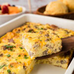 Removing a slice of the breakfast casserole with a spatula from the casserole dish.