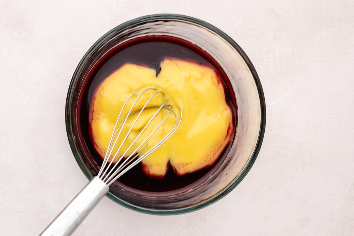 Wine and cream of chicken in a bowl with a whisk.
