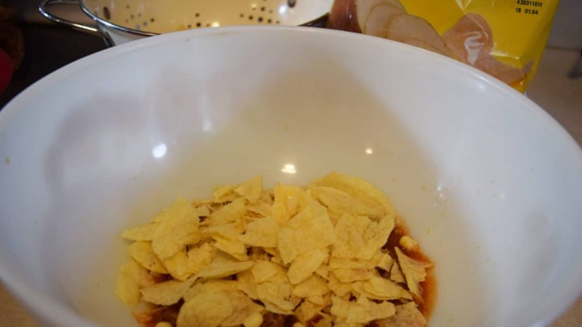 crushed potato chips in a shite bowl to be used in this recipe for mom\'s potato chip casserole
