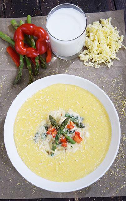 a bowl filled with a serving of these gouda grits with creamy asparagus and crab sauce