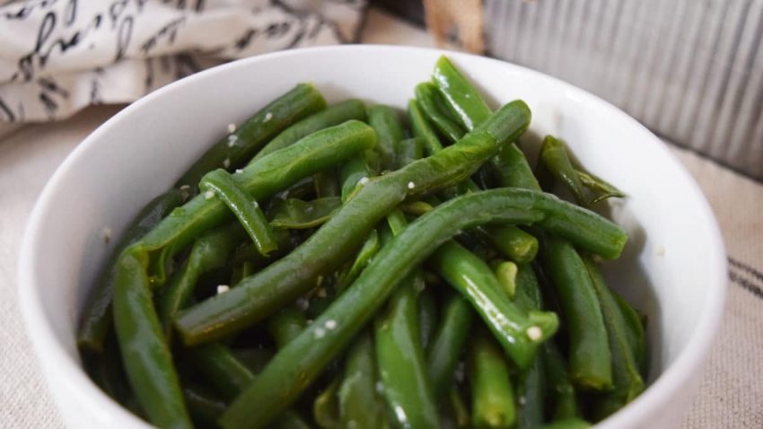  Instant Pot Green Beans in a white serving bowl sprinkled with coarsely ground salt.