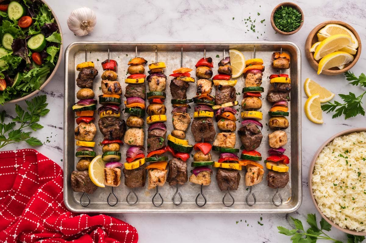 Grilled steak and chicken kabobs after being grilled set on a metal baking tray.