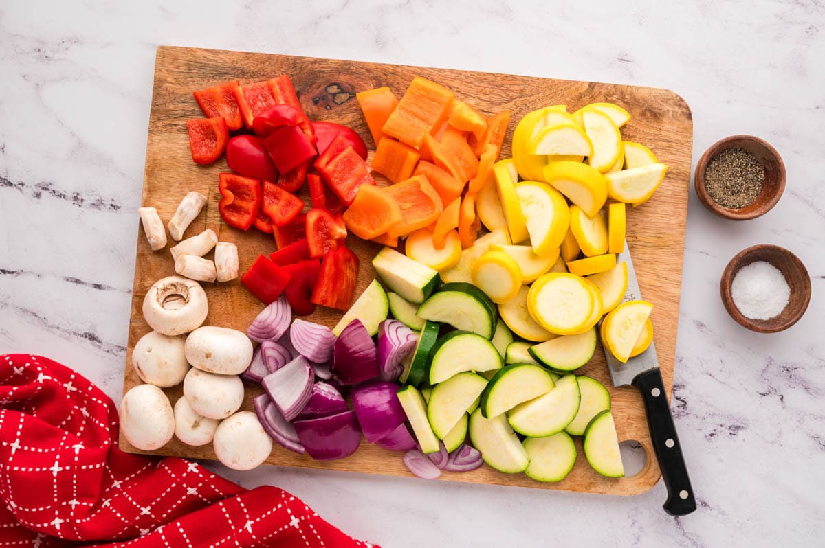 Cut veggies on a cutting board with a knife.