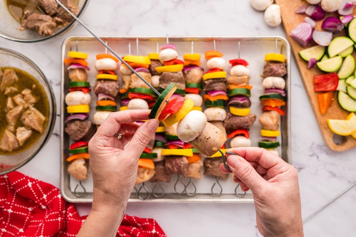 Threading skewers by hand with veggies, steak and chicken.