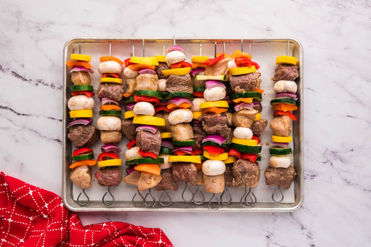 All the threaded kabobs on a baking tray lines with parchment paper.