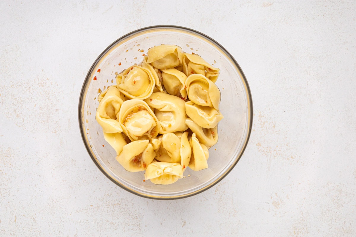 Tortellini marinated in zesty Italian dressing in. a bowl.