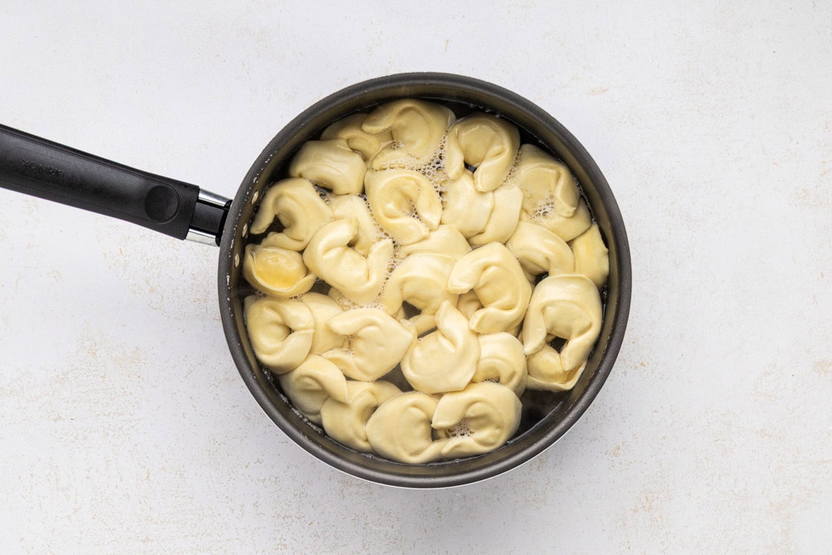 Tortellini cooking in a pot.