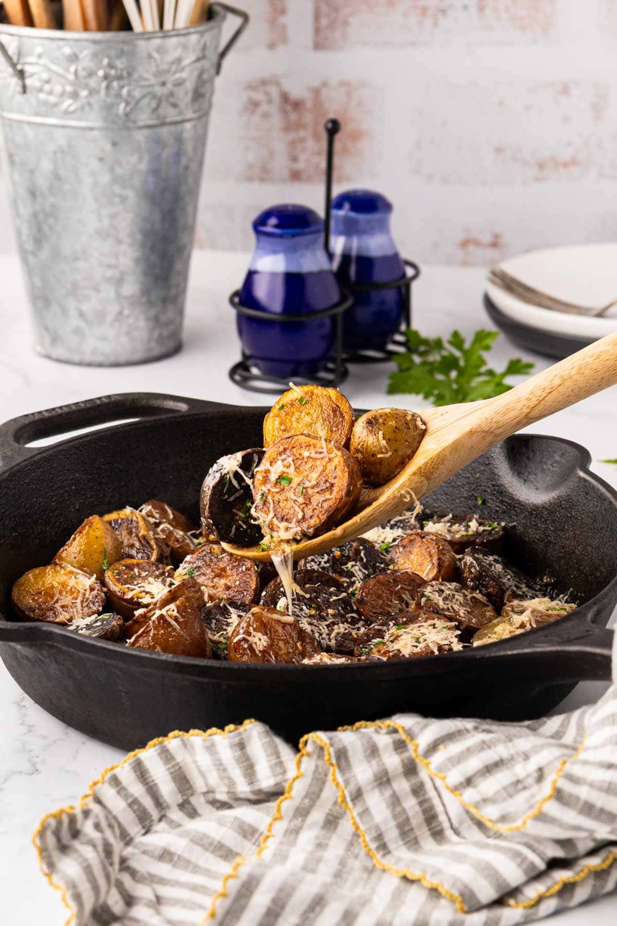 Removing potatoes from the skillet with a wooden spoon.