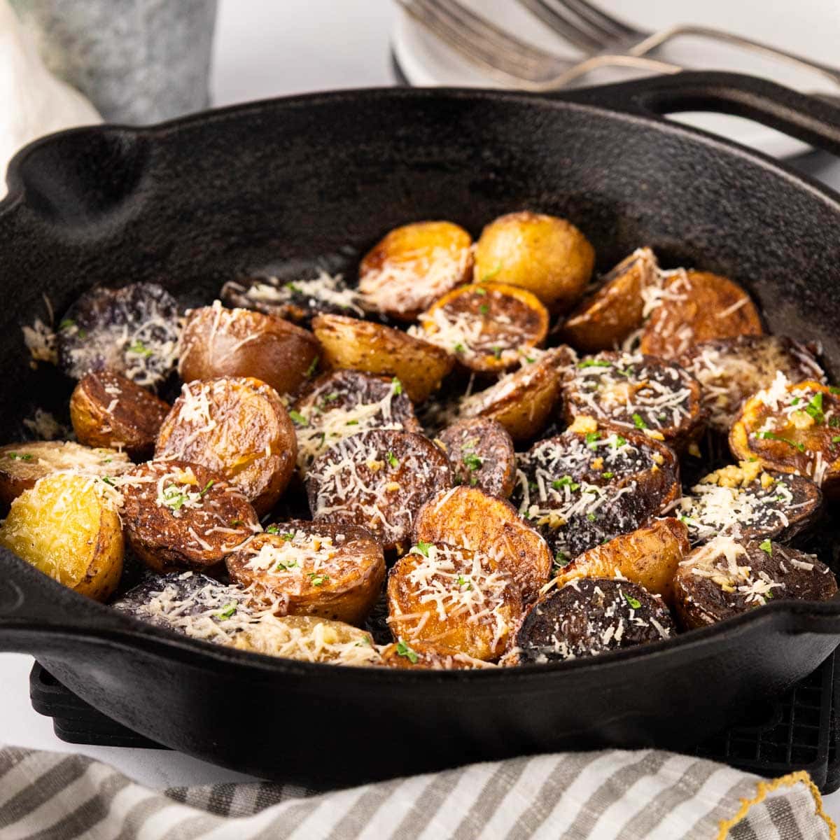 Freshly grated parmesan cheese melted over crispy potatoes in a skillet.