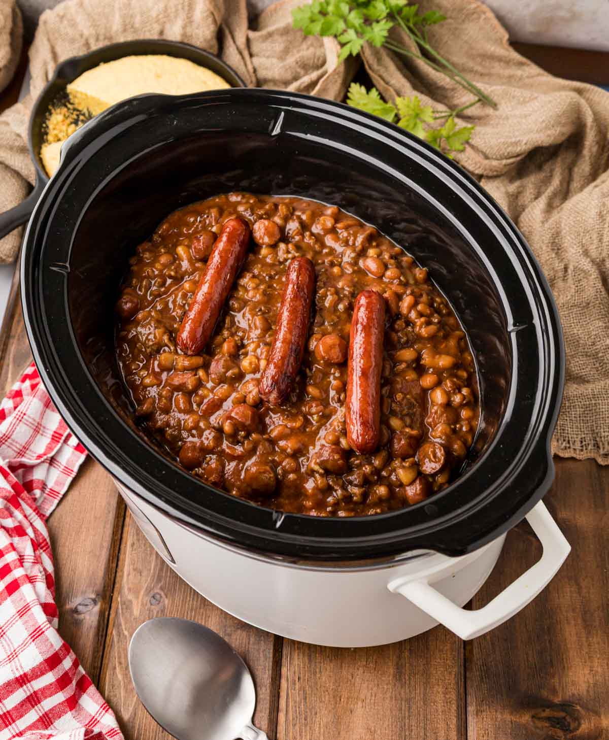 Cowboy Franks and Beans in a slow cooker garnished with full hot dogs on top.