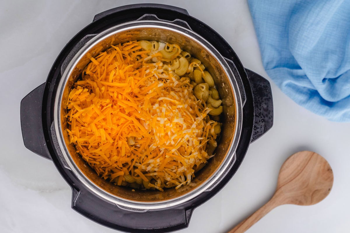 Shredded cheeses added to noodles in instant pot.