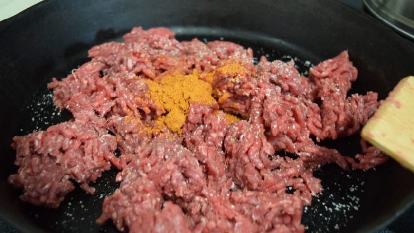 a closeup of ground beef with seasonings for this skillet beef queso dip recipe