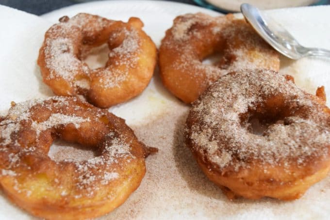 these fried green apples draining on a paper towel-lined plate with cinnamon sugar