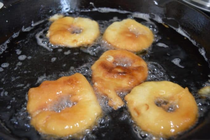 a closeup of these battered and fried green apple rings frying in a skillet